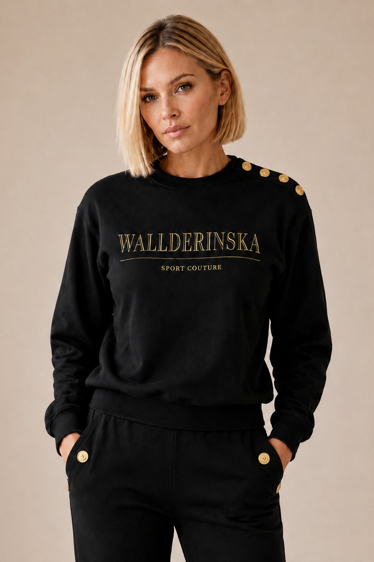 Edge Gold Button-settet i svart forfra, med hendene i bukselommene der gullknappene sitter.