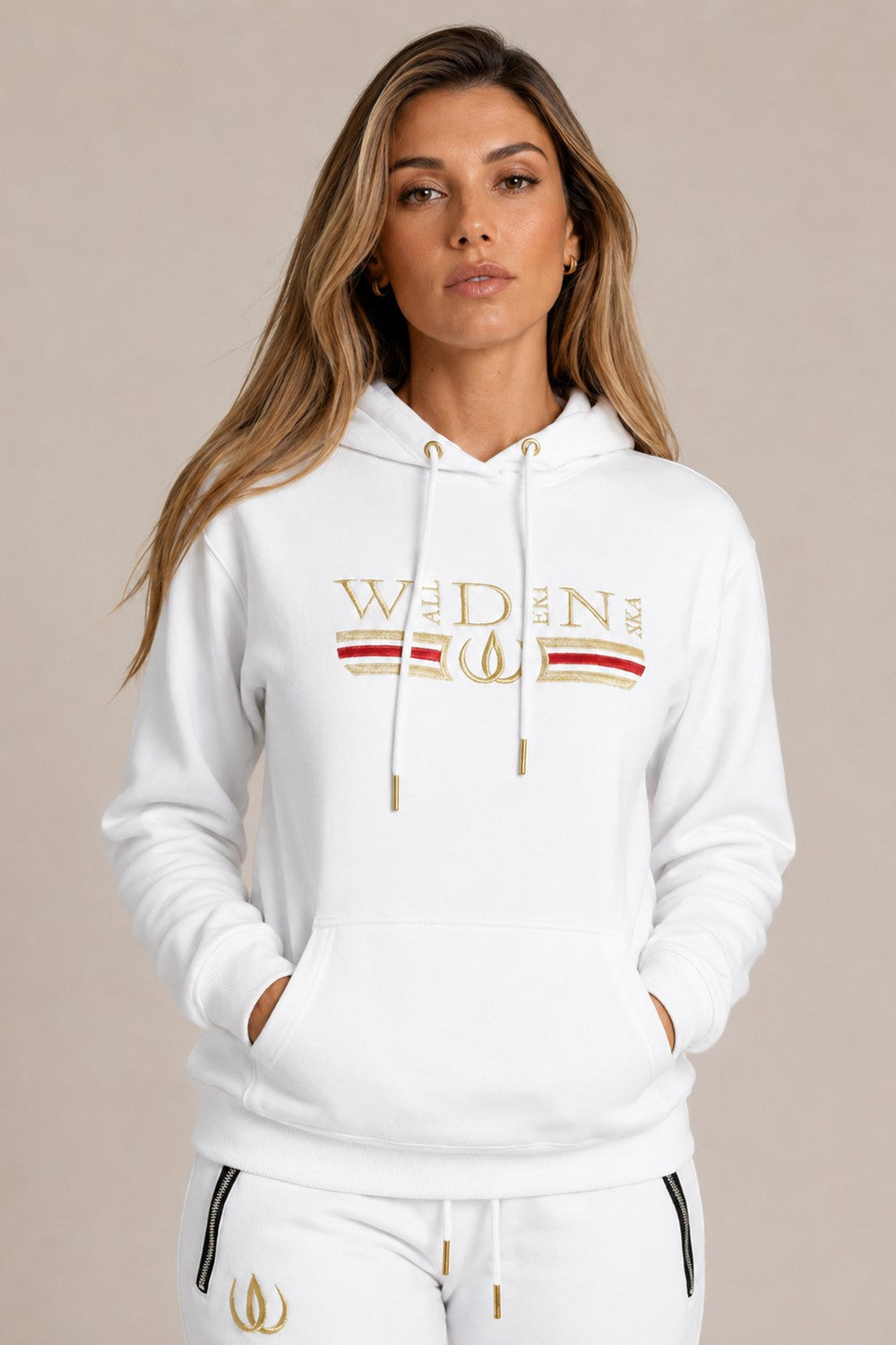 Hvit Deluxe Hoodie med gullbroderi og rød strek over brystet, båret til hvite Deluxe Joggers med gullogo.