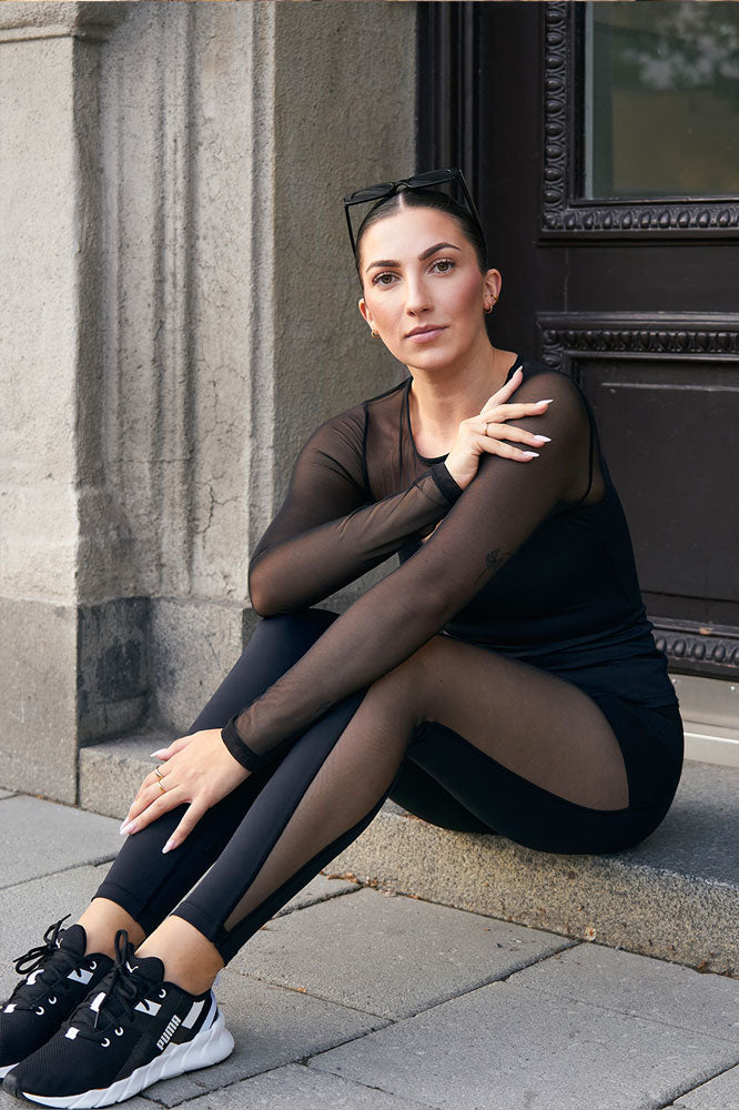 På en trapp i byen bæres genseren til svarte tights med gjennomsiktig kile langs benet.