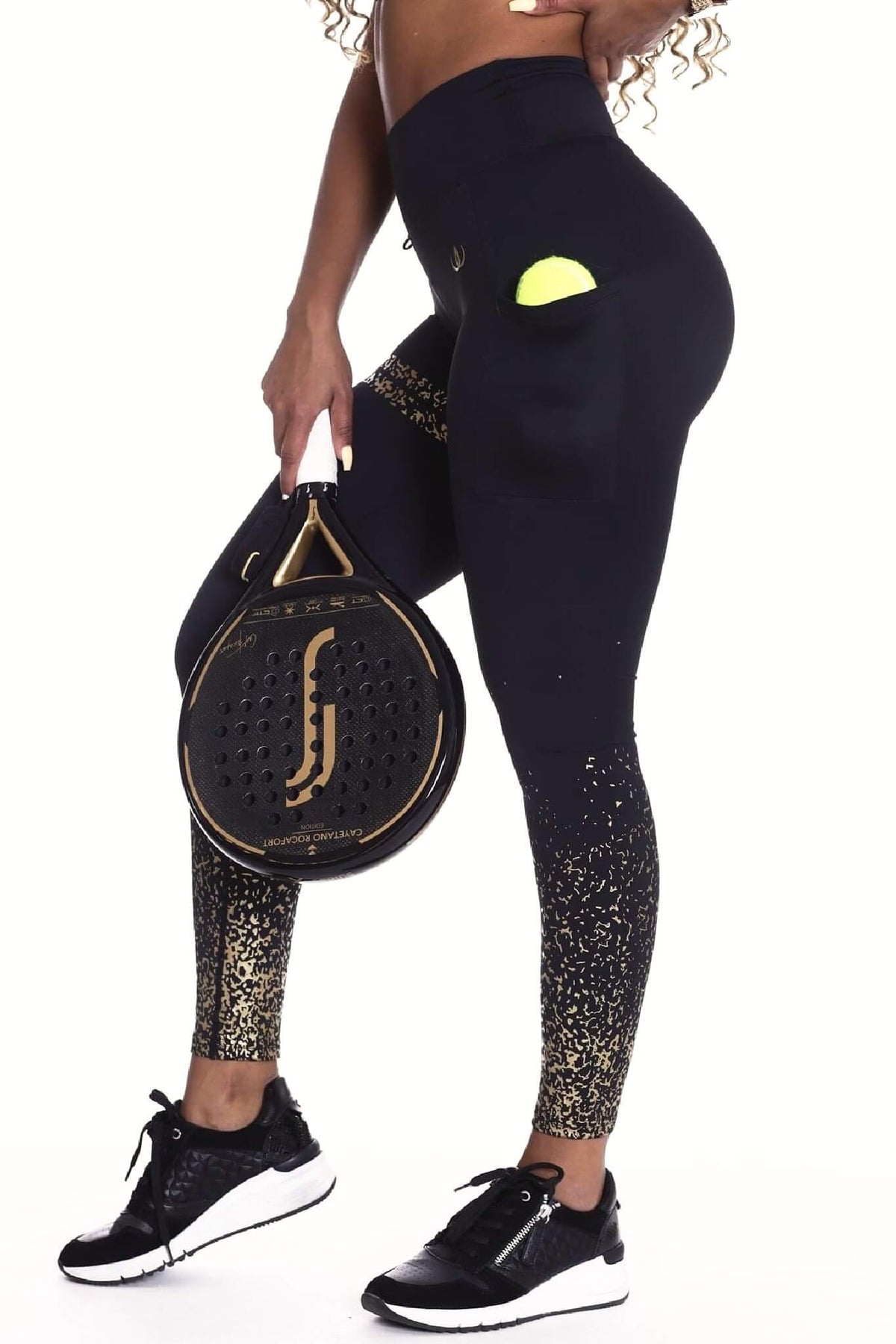 En ball i lommen på de svarte tightsen mens modellen holder opp en padelracket.